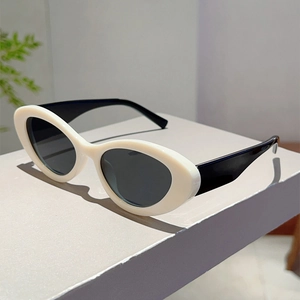 Cat eye sunglasses with ivory frame and black wide temples on a minimal geometric pedestal
