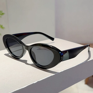 Close-up of retro black oval sunglasses with thick frames on a minimalist white stand