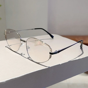Detail shot of silver metal frame sunglasses with transparent lenses on a white surface