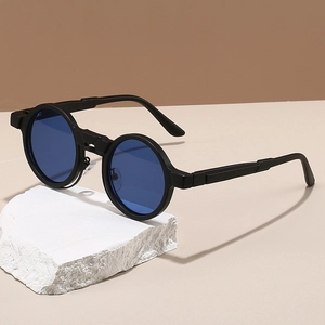 Detail of round steampunk sunglasses with dark blue lenses on a white stone base