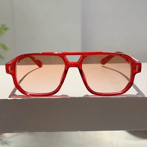 Detailansicht der roten transparenten Sonnenbrille mit goldenen Pfeil-Metallakzenten