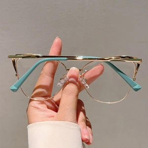 Détail de lunettes en métal doré avec double pont et embouts de branches bleu canard