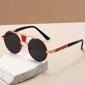 Close-up of retro round metal sunglasses with red frame and gold hollow double bridge