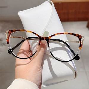 Detail of tortoiseshell cat-eye glasses with gold metal temples on a white leather case