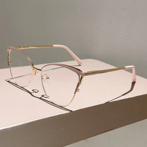 Détail d'une monture de lunettes oeil-de-chat or rose sur un socle géométrique beige