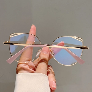 Detailed shot of golden cat-eye metal glasses frame with hollow design and pink tips