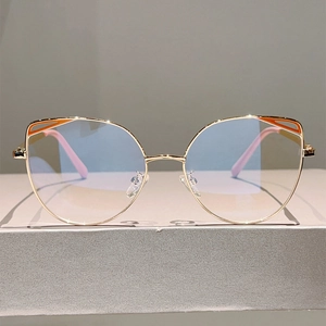 Detail of cat-eye gold metal frames with orange cutout accents and pink temple tips