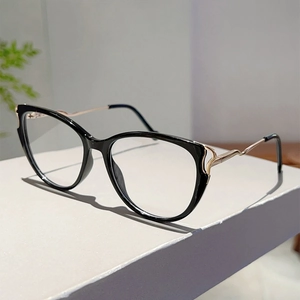 Close-up of cat-eye glasses with glossy black frames and wavy golden metal temples