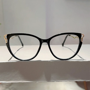 Close-up of black cat-eye glasses with golden wave pattern metal accents on the temple