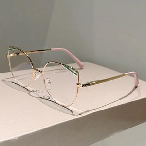 Chic cat-eye metal frame glasses in gold with pink temple tips on a minimalist stand