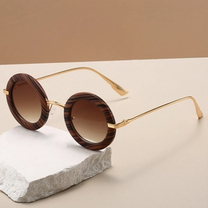 Detail of round vintage sunglasses with textured frames and gold metal temples on stone