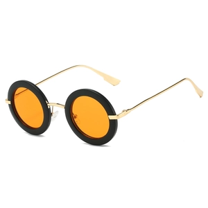 Detail of retro round sunglasses with black frames, orange lenses, and gold metal temples