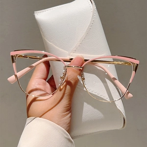 Lunettes œil de chat roses avec monture dorée et étui blanc tenues à la main