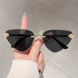 Détail de lunettes de soleil œil-de-chat sans monture avec pont doré et gravures