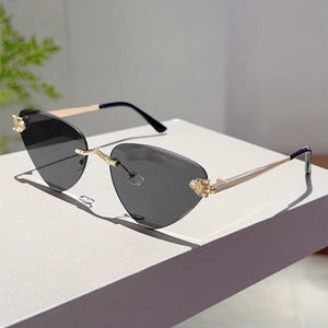 Détail de lunettes de soleil œil-de-chat sans monture avec charnières dorées et verres gris
