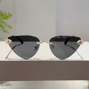 Détail de lunettes de soleil œil-de-chat sans monture avec pont en V doré et verres gris