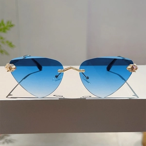 Détail de lunettes de soleil sans monture à dégradé bleu avec pont doré géométrique