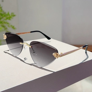 Détail de lunettes de soleil œil-de-chat sans monture avec branches dorées et verres dégradés