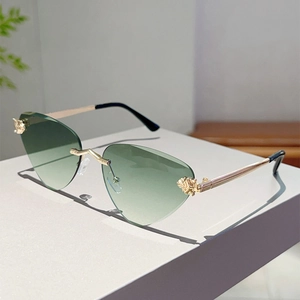 Détail de lunettes de soleil cœur sans monture avec verres dégradés verts et branches en or