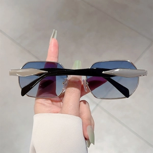 Detail of silver octagonal metal frame sunglasses with blue gradient lenses held by hand