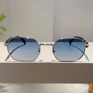 Detail of silver metal octagonal sunglasses with blue gradient lenses on white surface