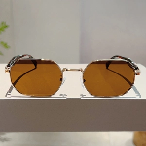 Detail view of gold octagonal sunglasses with brown lenses and tortoiseshell temple tips