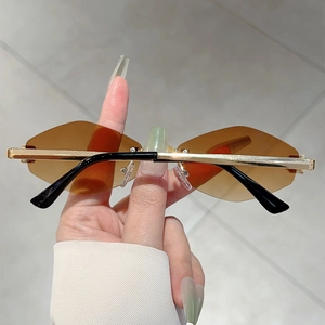 Dettaglio occhiali da sole senza montura color ambra con eleganti aste dorate
