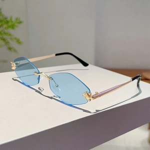 Dettaglio di occhiali da sole geometrici senza montatura blu con incisioni in oro