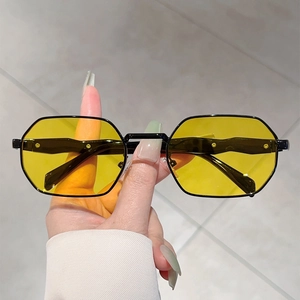 Vintage polygonal sunglasses with yellow lenses and black metal frame in a hand-held view
