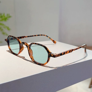 Detail shot of tortoise shell geometric frames with light green lenses on a white pedestal