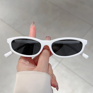 Close-up of stylish oval white frame sunglasses with dark lenses held by hand
