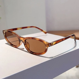 Detail view of oval tortoise shell sunglasses with brown lenses on a white display stand