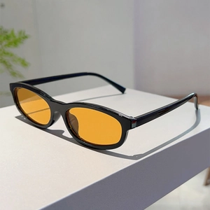 Detail of vintage oval sunglasses with black frames and orange tinted lenses for fashion