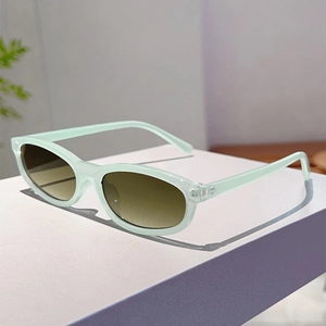 Detail shot of oval mint green sunglasses with gradient brown lenses on a white stand