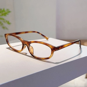 Detail view of oval tortoiseshell sunglasses on a geometric stand with plants