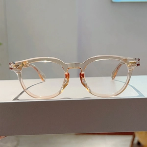Detail view of transparent champagne round glasses frame with gold metal rivets