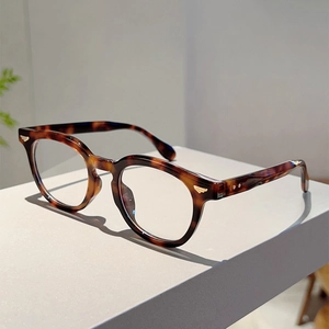 Detail view of tortoiseshell eyeglasses frame featuring golden feather metal accents