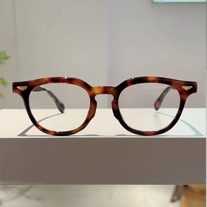 Close-up of tortoise shell round eyeglass frames with golden wing metal hardware