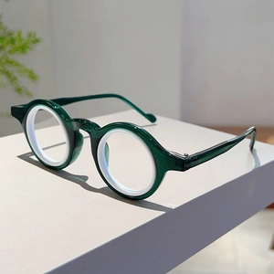 Vue détaillée des lunettes rondes avec monture vert foncé et anneau intérieur blanc