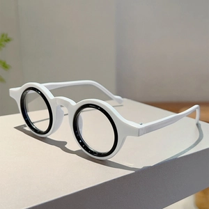 Détail de lunettes rondes avec design bicolore noir et blanc sur un support élégant