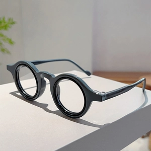Détail de lunettes rétro à monture ronde gris foncé sur une surface minimaliste moderne