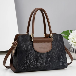 Elegant black snake-pattern handbag with brown handles and gold hardware in studio setting