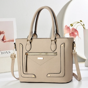 Detail of beige lychee grain leather handbag featuring gold hardware and zippers
