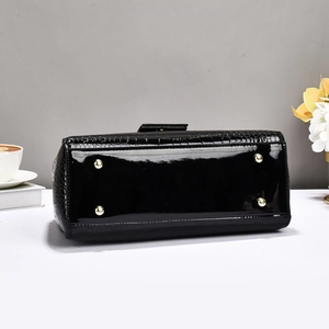 Detail view of the crocodile embossed black patent leather bag with gold protective feet