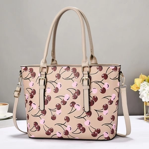 Detail of cherry print tote bag featuring golden hardware and detachable shoulder strap