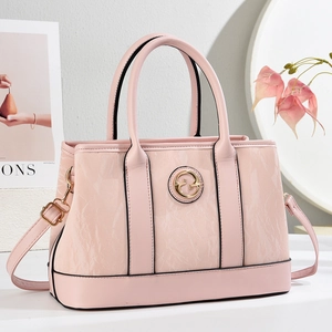 Elegant pale pink leather handbag with gold circular logo and adjustable strap