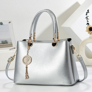 Detail of silver lychee texture handbag with golden dreamcatcher pendant and metallic finish