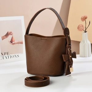 Detailed macro shot of dark brown lychee grain leather bucket bag with golden padlock