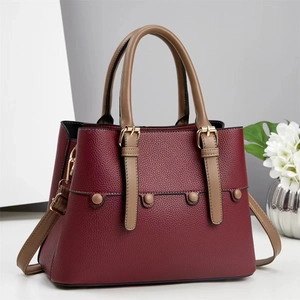 Close-up of wine red textured leather handbag with gold buckle and stylish rivets