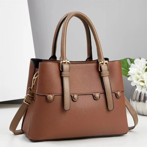 Detail of a brown lychee pattern leather crossbody bag with golden hardware and decor